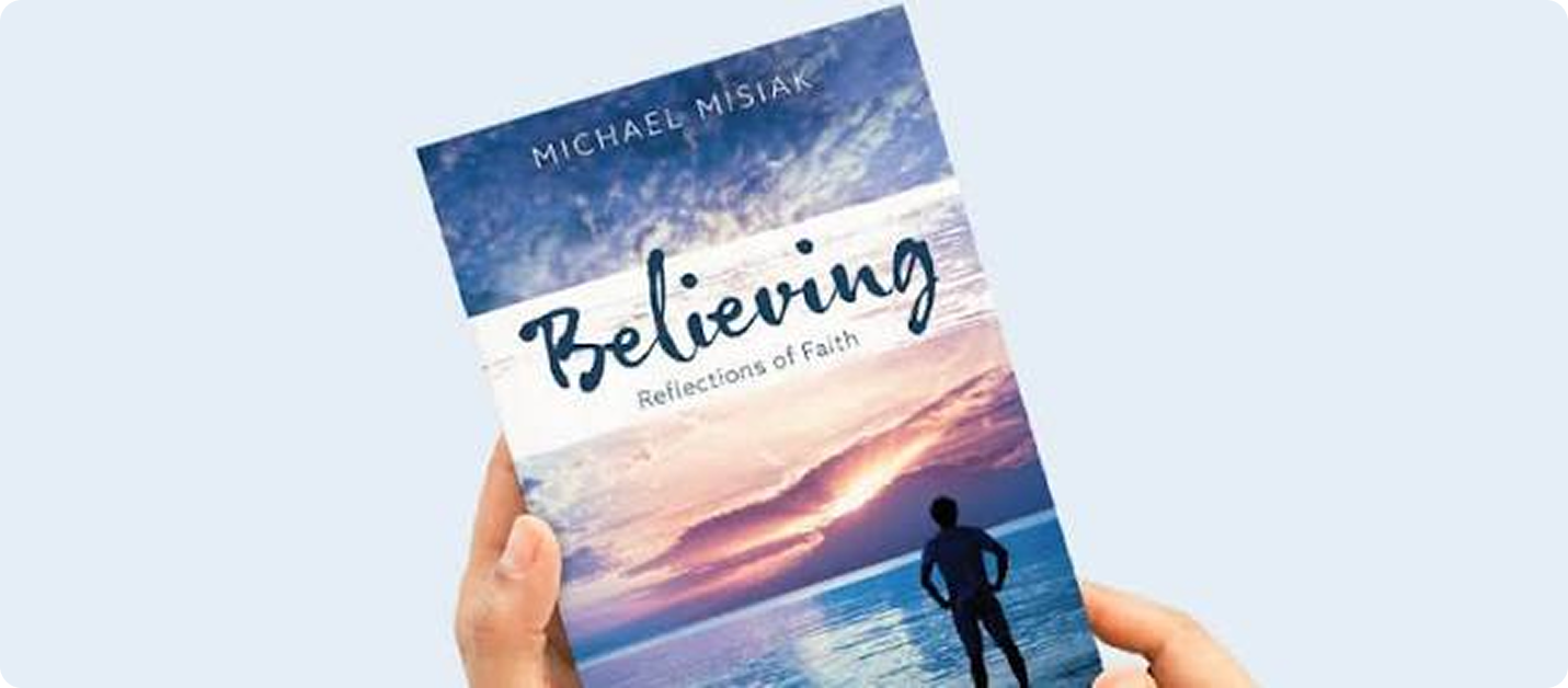 Hands holding up paperback book Believing Reflections of Faith by Michael Misiak