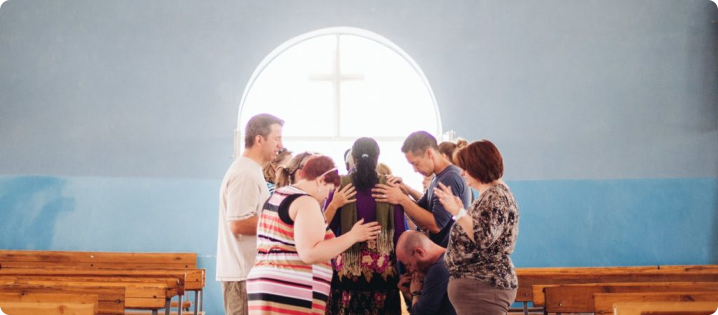 Group of people praying together inside a church hall