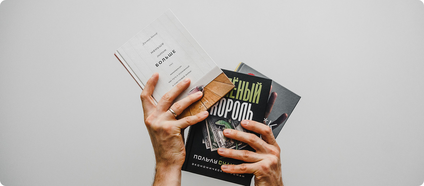Two hands grasping a stack of Russian paperback books with bold, colorful covers