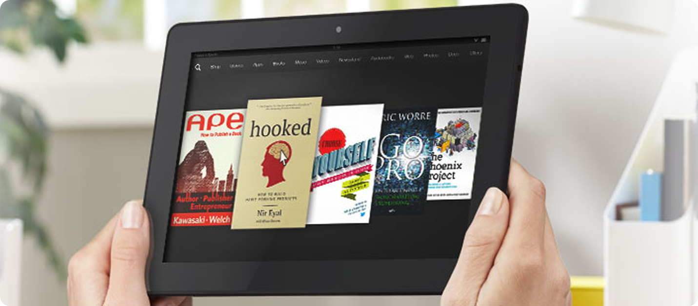Hands holding tablet displaying row of ebook cover thumbnails